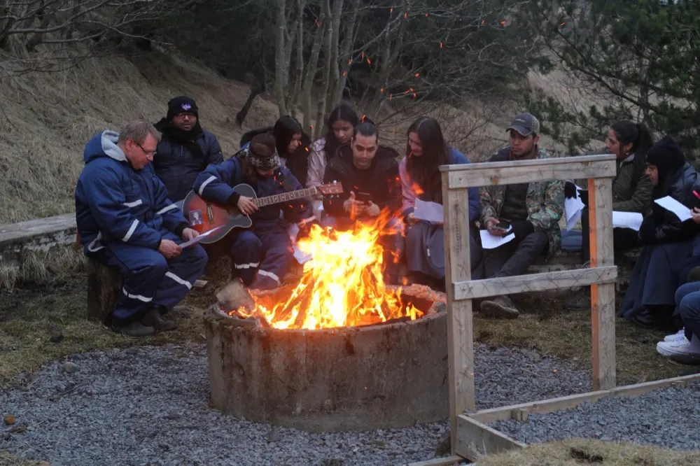 Un grupo canta alrededor de una fogata al anochecer