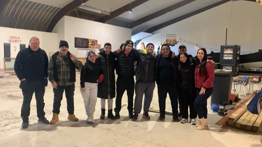 Voluntarios abrazados dentro de una bodega